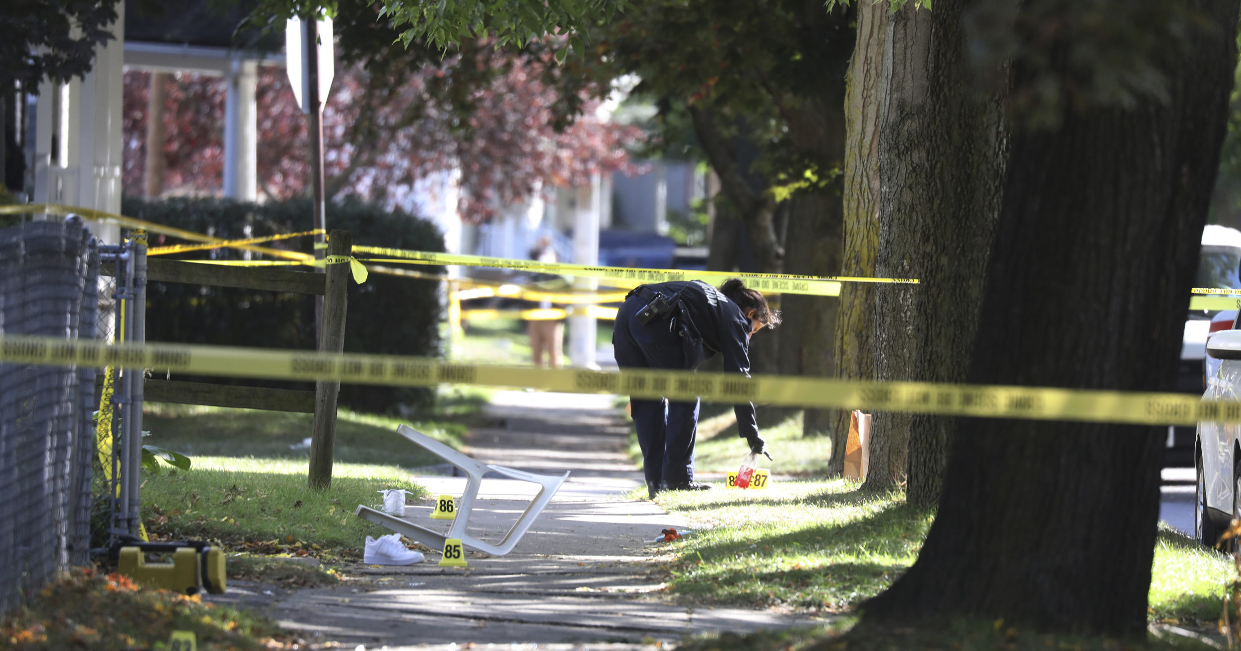 A Rochester police technician picks up items as evidence near the home where a fatal shooting took place on Sept. 19, 2020, in Rochester, New York.