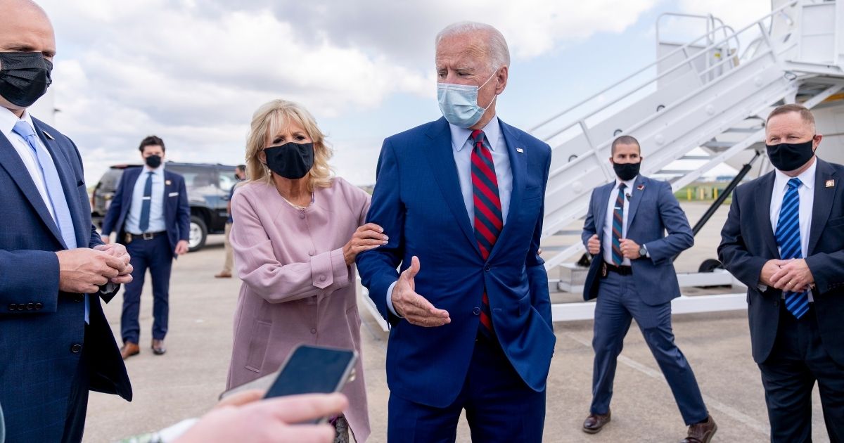 Jill Biden pulls the arm of her husband, Democratic presidential nominee Joe Biden, as he speaks to reporters before boarding his campaign plane at New Castle Airport in New Castle, Delaware, on Oct. 5, 2020, to travel to Miami.