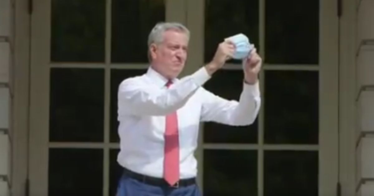 New York Mayor Bill de Blasio holds up a mask before putting it on.