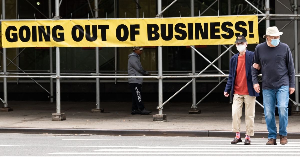 People wearing protective masks walk by a "going out of business" sign displayed on the Upper West Side on Sept. 27, 2020, in New York City.