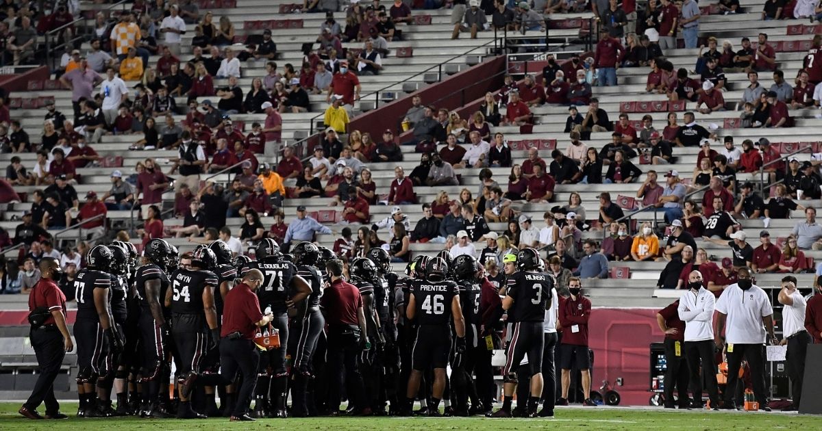 Socially distanced fans look on as the South Carolina Gamecocks huddle during a stoppage in play of their football game against the Tennessee Volunteers at Williams-Brice Stadium Columbia, South Carolina, on Saturday.