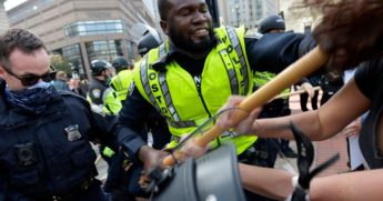 A counterprotester grabs an officer's baton as leftist demonstrators clash with officers outside a gathering of the pro-Trump Super Fun Happy America group in Boston's Copley Square on Sunday.