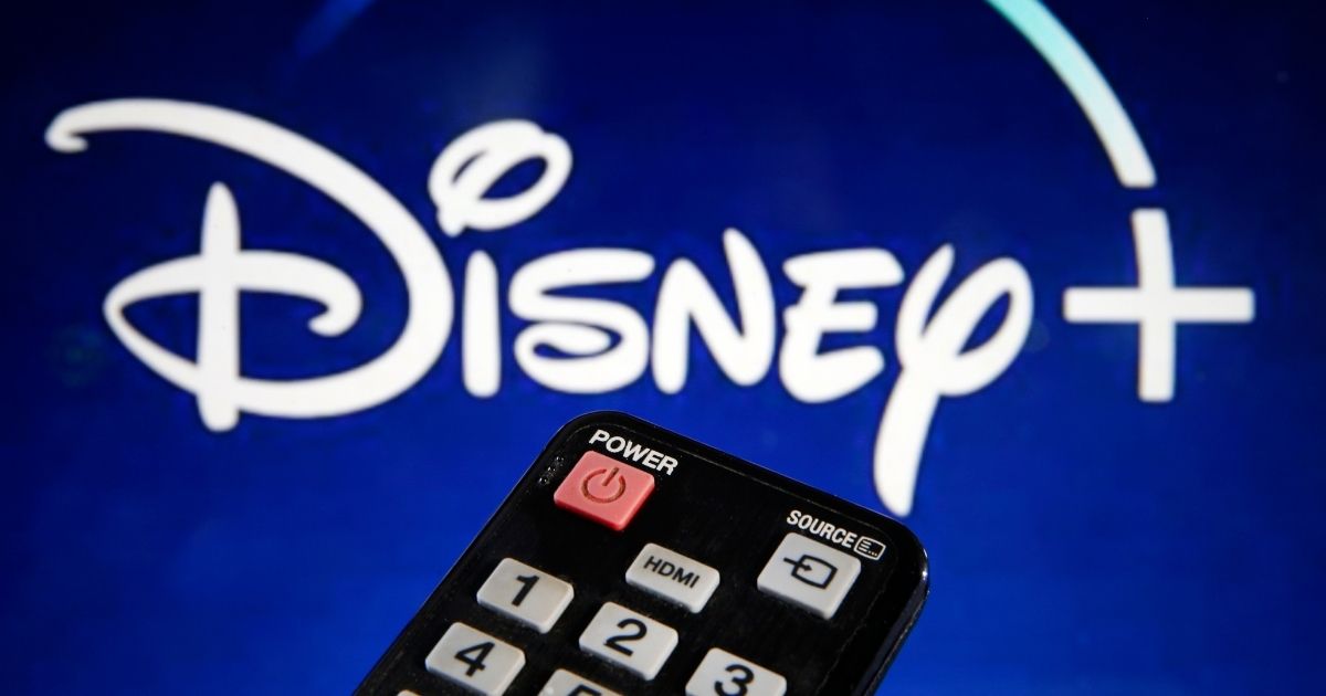 A remote control is seen in front of a television screen showing a Disney Plus logo on March 28, 2020, in Paris.