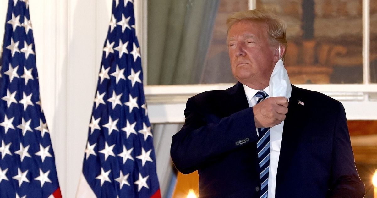 President Donald Trump removes his mask upon his return to the White House from Walter Reed National Military Medical Center on Monday.