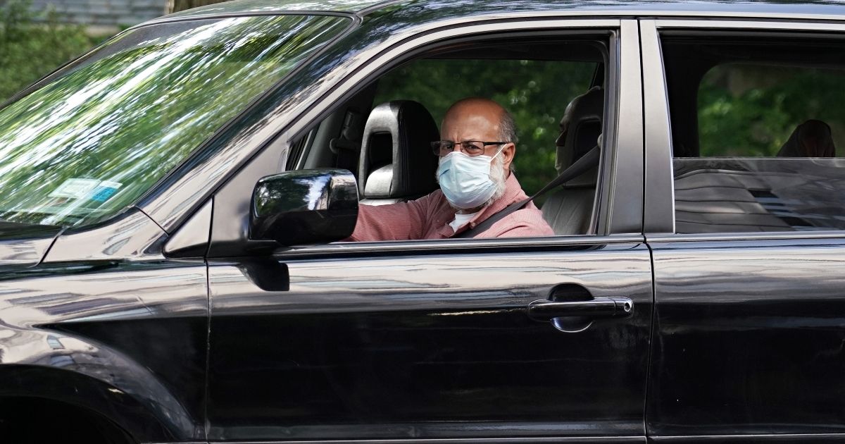A man wearing a protective mask drives a car during the coronavirus pandemic on May 20 in New York City.