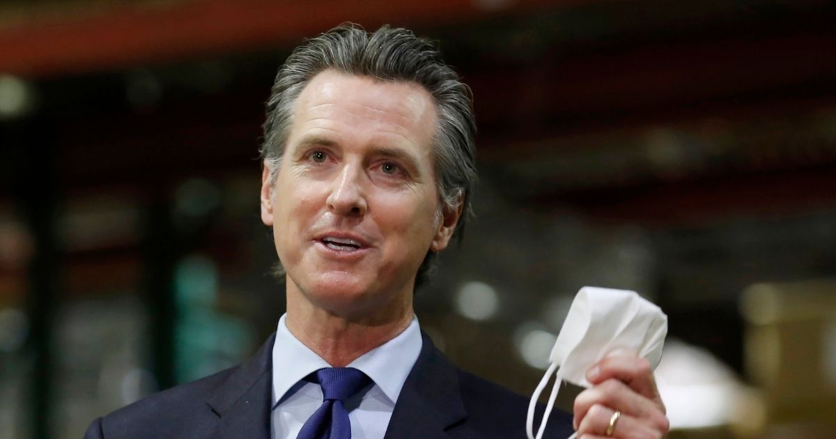 California Gov. Gavin Newsom holds a face mask as he urges people to wear them to fight the spread of the coronavirus during a news conference in Rancho Cordova, California, on June 26, 2020.