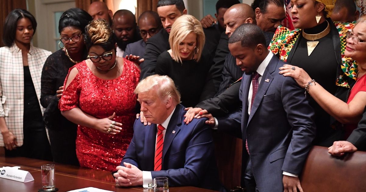 African-American and faith leaders pray over President Donald Trump in the Cabinet Room of the White House in Washington on Feb. 27, 2020.
