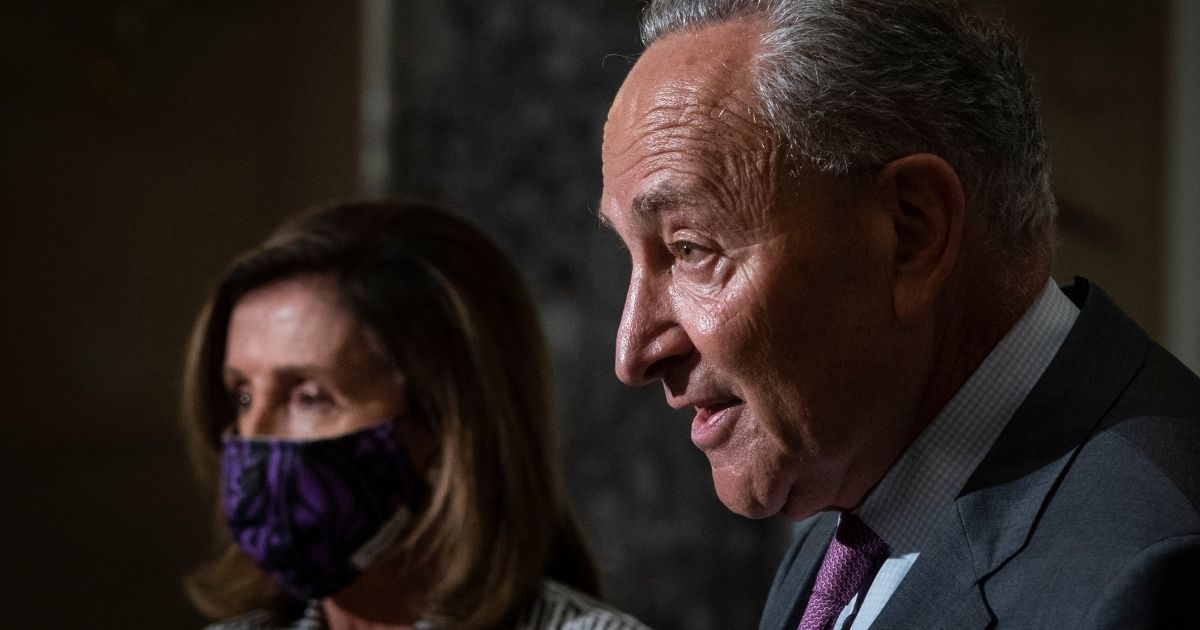 Senate Minority Leader Chuck Schumer of New York speaks to reporters while House Speaker Nancy Pelosi of California looks on during a news conference at the Capitol in Washington on July 28, 2020.
