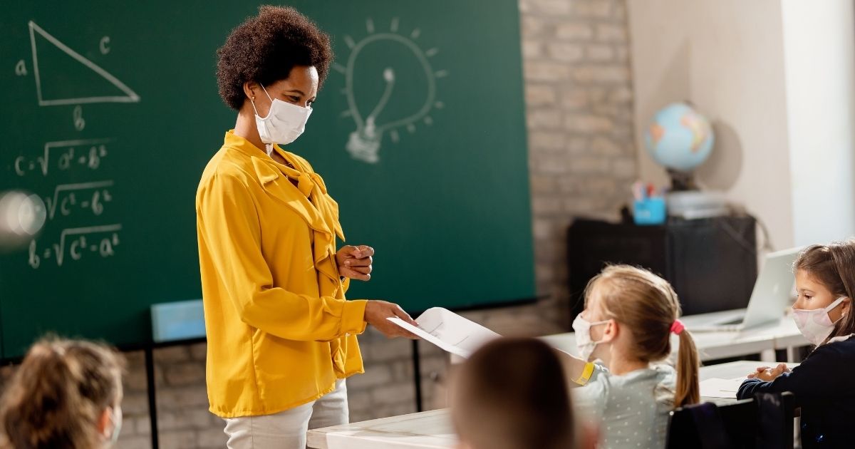 A teacher interacts with a student in the stock image above.