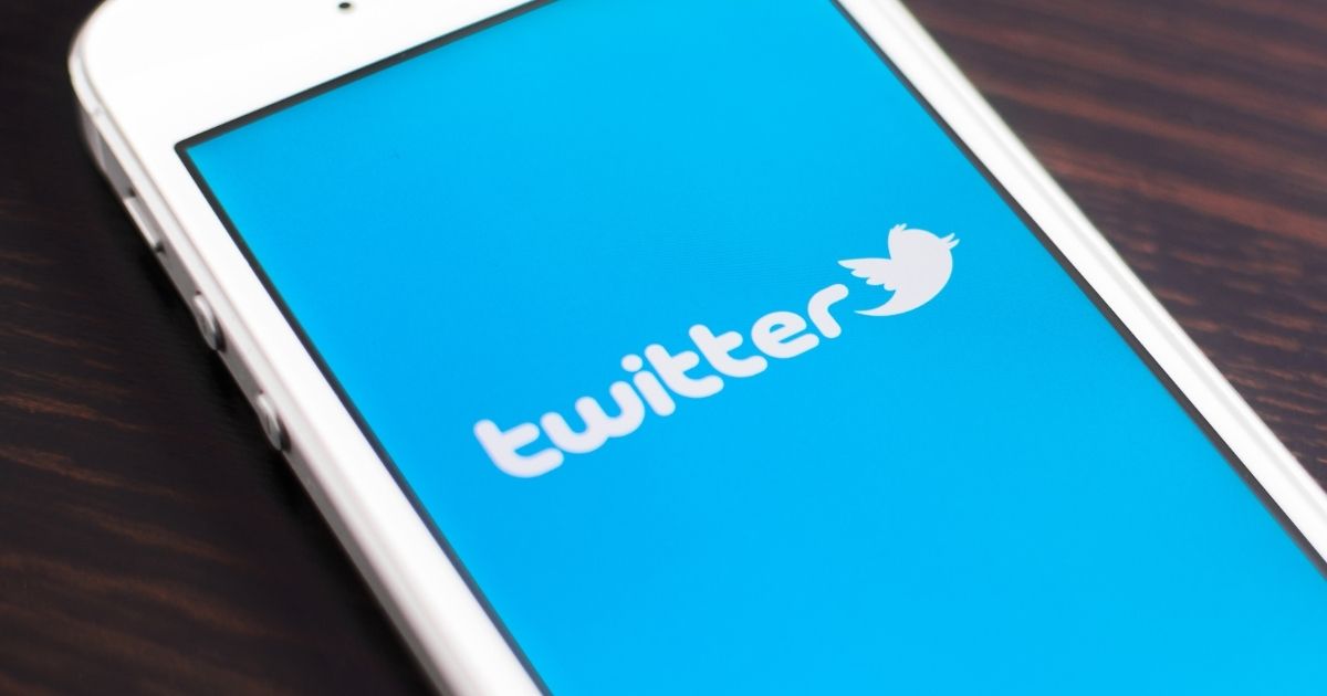 The Twitter logo is pictured on a phone in the stock image above.