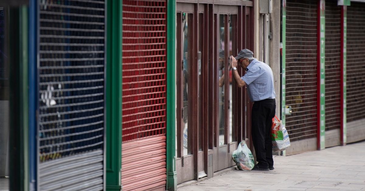 A man looking into a shuttered UK coffee shop during the country's May lockdown.