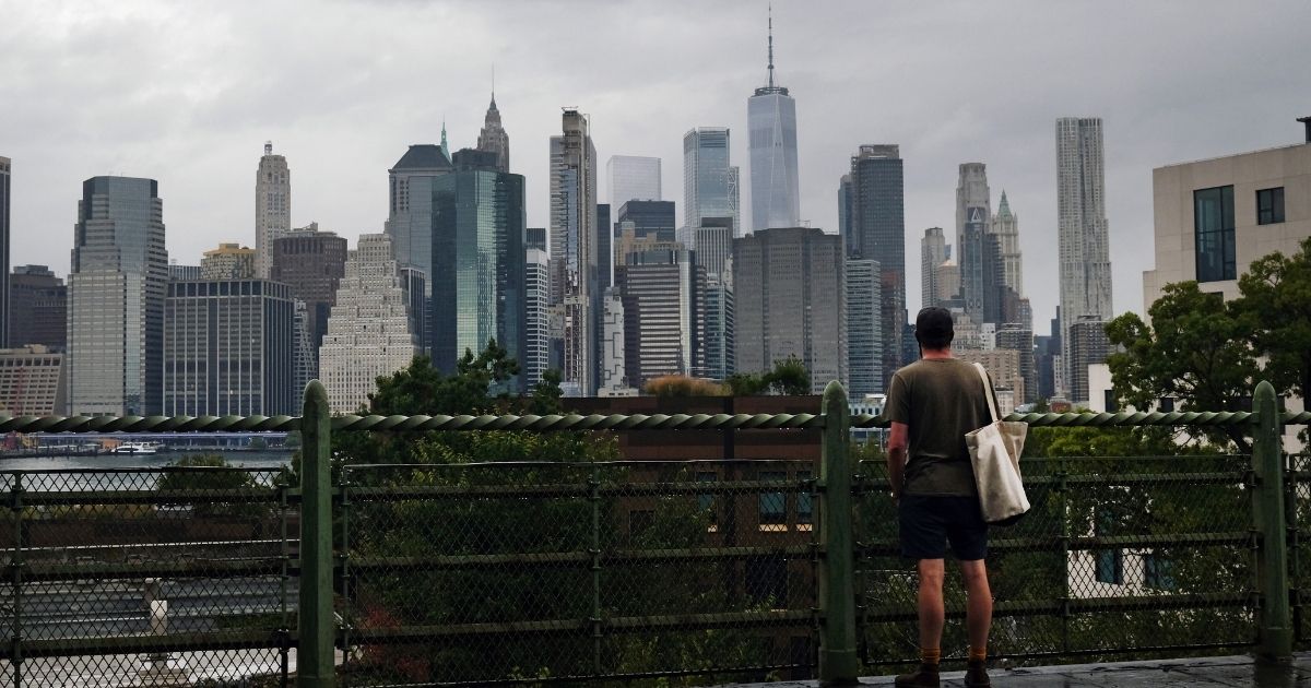 A man looks at the Manhattan skyline from a Brooklyn neighborhood on Sept. 29, 2020, in New York City, which is facing a crisis in the tourism industry.