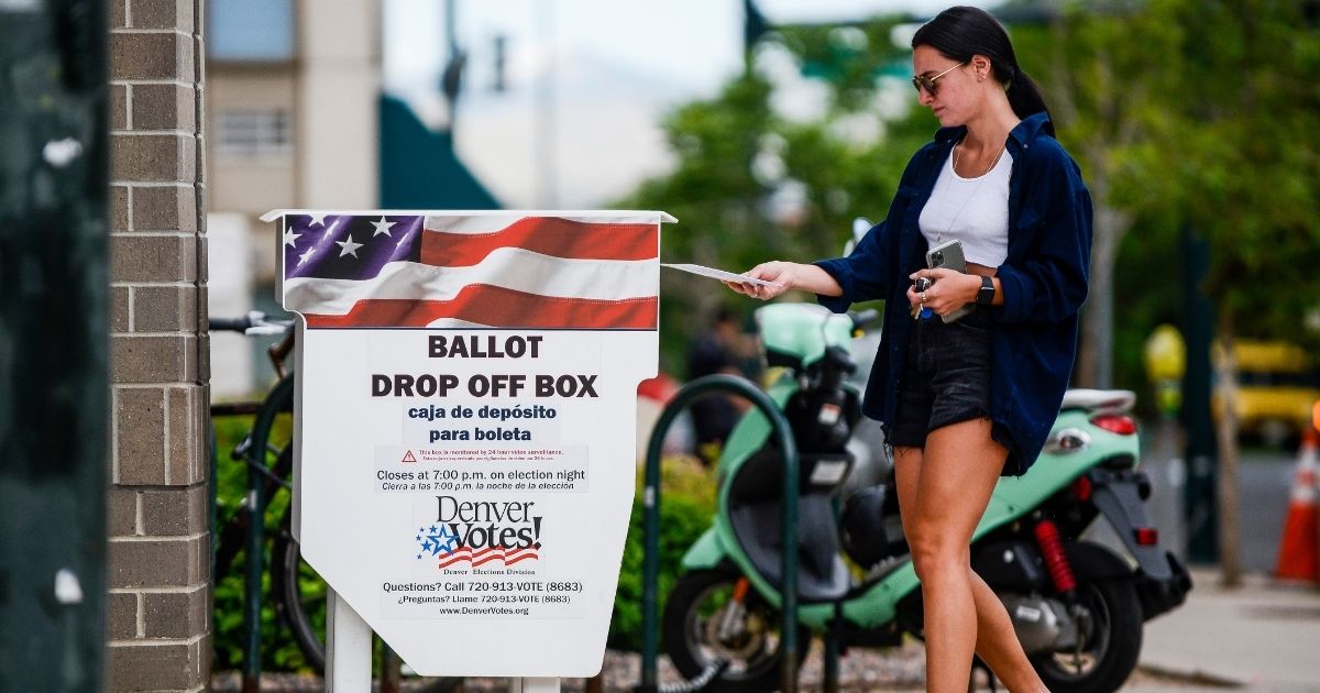 DENVER, CO - JUNE 30: A woman drops off her main in ballot outside the Denver Elections Division polling center as she votes in the primary election on June 30, 2020 in Denver, Colorado. Voters will decide between former Gov. John Hickenlooper and former Colorado House of Representatives Speaker Andrew Romanoff to face off in the November U.S. Senate race against Sen. Cory Gardner.