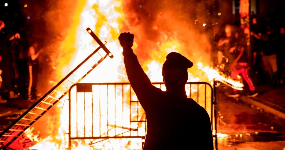 TOPSHOT - A protester raises a fist near a fire during a demonstration outside the White House over the death of George Floyd at the hands of Minneapolis Police in Washington, DC, on May 31, 2020. - Thousands of National Guard troops patrolled major US cities after five consecutive nights of protests over racism and police brutality that boiled over into arson and looting, sending shock waves through the country. The death Monday of an unarmed black man, George Floyd, at the hands of police in Minneapolis ignited this latest wave of outrage in the US over law enforcement's repeated use of lethal force against African Americans -- this one like others before captured on cellphone video.