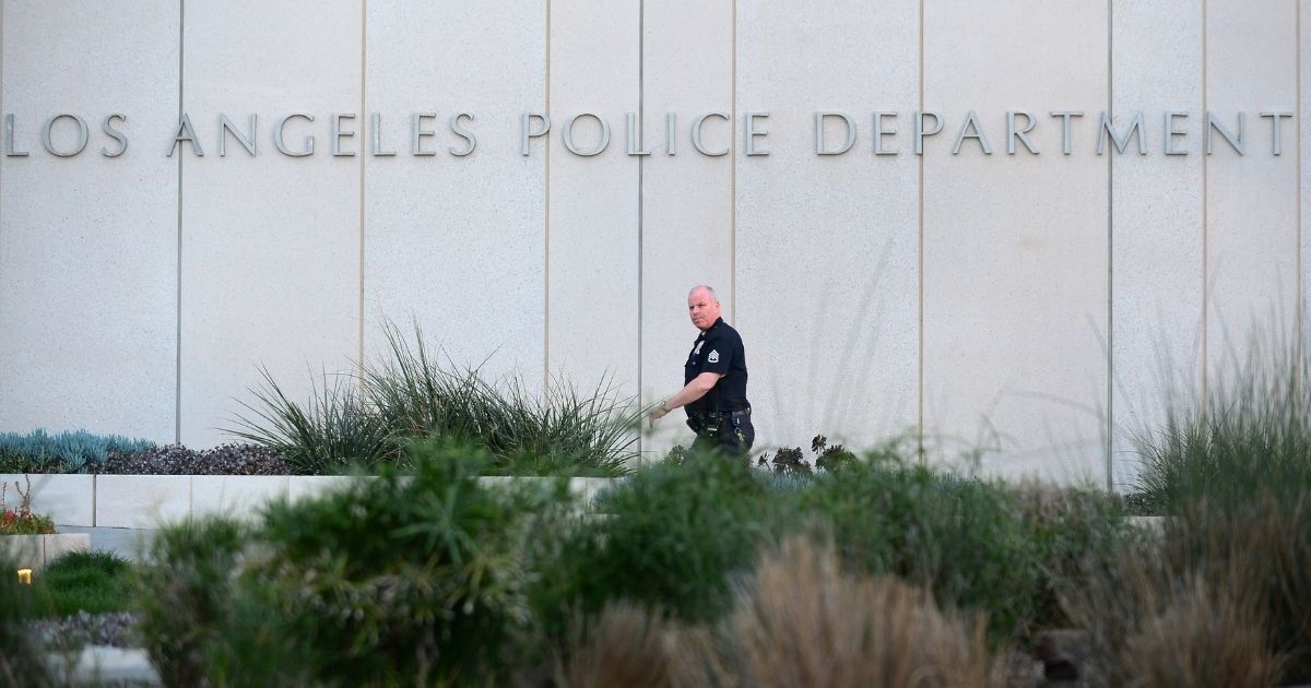 A Los Angeles Police Department (LAPD) officer walks to police headquarters in downtown Los Angeles on February 12, 2013 in California, where media are gathered in regards to the case of suspected cop killer Christopher Dorner. The LA Times reported a single gunshot was heard as police moved in on a mountain cabin where Dorner was believed to be barricaded in Big Bear, some 100 miles east of downtown Los Angeles. Meanwhile, a Los Angeles Police Department (LAPD) spokesman was cited as saying the force believed Dorner died inside the burning cabin in the mountains.