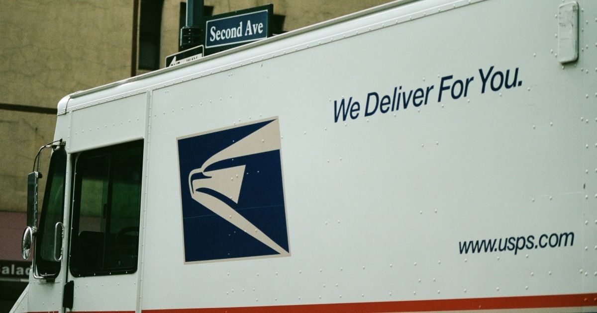 Close-up of logo on a United States Postal Service (USPS) mail truck with tagline reading 'We Deliver For You' driving down 2nd Avenue in Manhattan, New York City, New York, September 15, 2017.