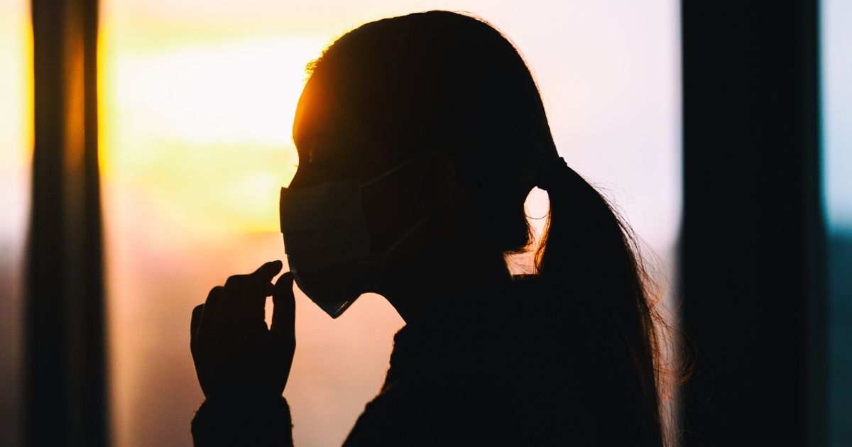 A woman touches her face mask for COVID-19 prevention.