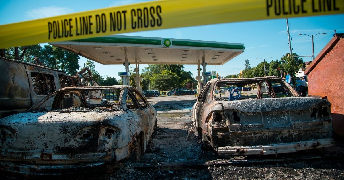 Cars stand burned in the lot of the BP gas station after rioters clashed with the Milwaukee Police
