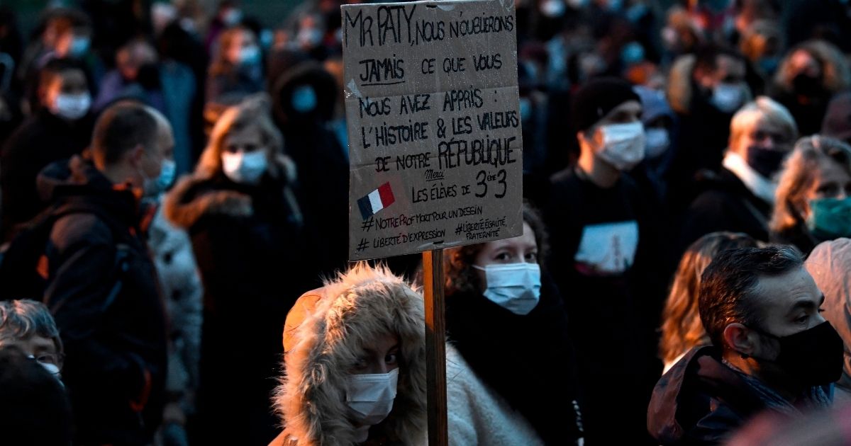 A woman holds a sign reading 'Mr. Paty, we will never forget what you taught us: history and the values of the Republic' during a march on Oct. 20, 2020, in Conflans-Sainte-Honorine, northwest of Paris, after a teacher was beheaded for showing pupils cartoons of Muhammad.