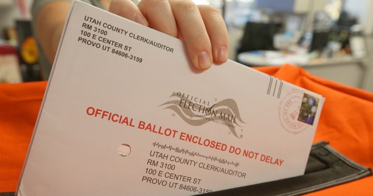 An employee puts a mail-in ballot into a container to register the vote in the midterm elections on Nov. 6, 2018, in Provo, Utah.
