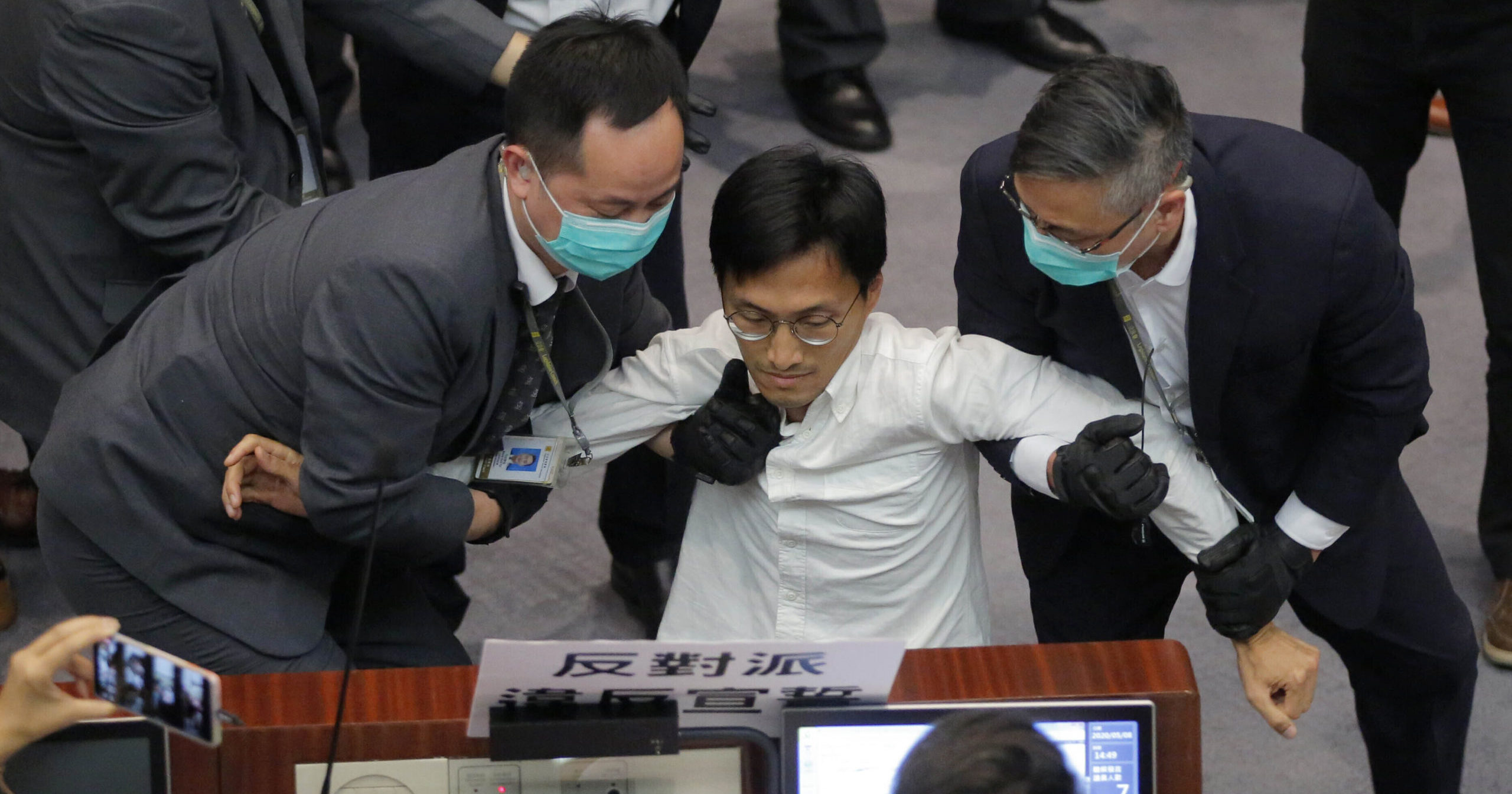 In this May 8, 2020, file photo, pro-democracy lawmaker Eddie Chu is taken away by security guards during a legislative meeting in Hong Kong.