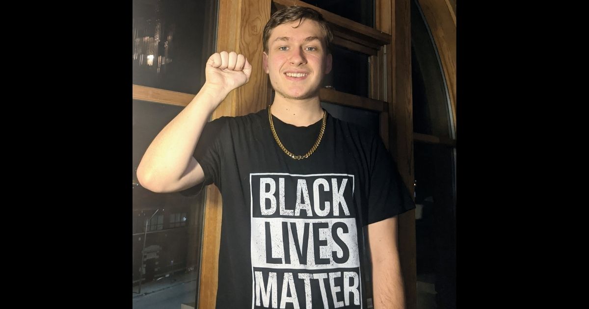 Aaron Coleman raises his fist while wearing a "Black Lives Matter" shirt.