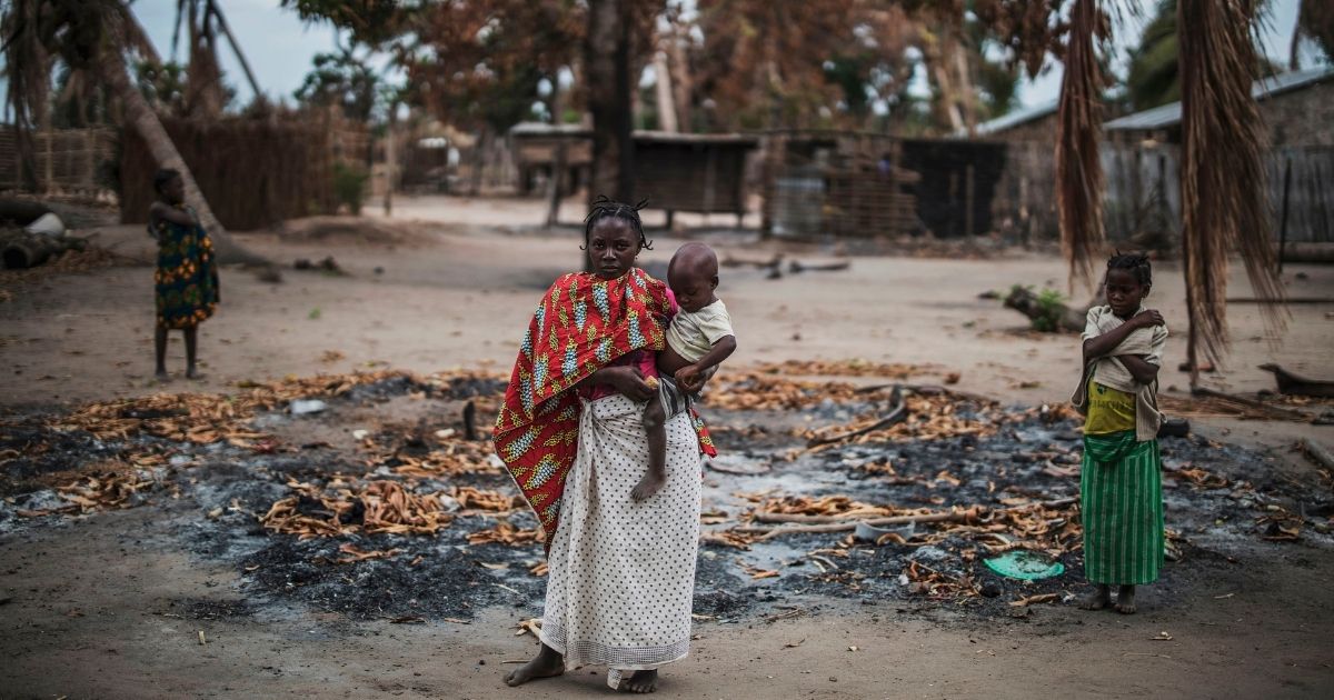 A woman holds her younger child while standing in a burned out area in the village of Aldeia da Paz outside Macomia, on Aug 24, 2019. The village had been attacked earlier that month.