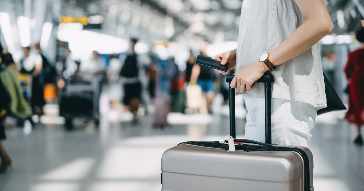 The stock photo above shows a woman with a suitcase in an airport.