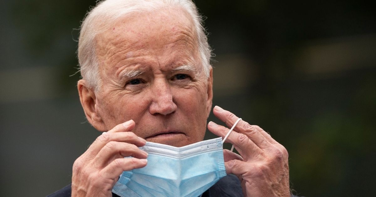Democratic presidential nominee Joe Biden puts on a face mask while speaking to reporters at a voter mobilization center in Chester, Pennsylvania, on Oct. 26.