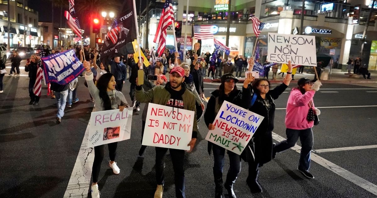 Demonstrators march across the Pacific Coast Highway while shouting slogans in protest of Gov. Gavin Newsom's strict stay-at-home orders Saturday in Huntington Beach, California.