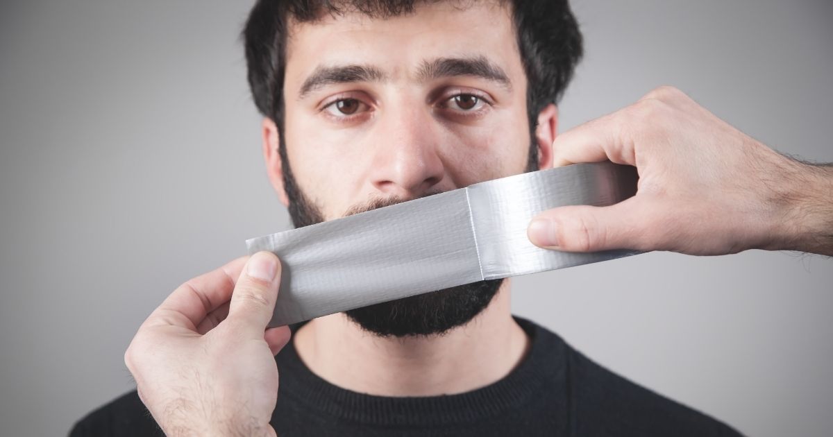 A man has his mouth taped shut in the stock image above.