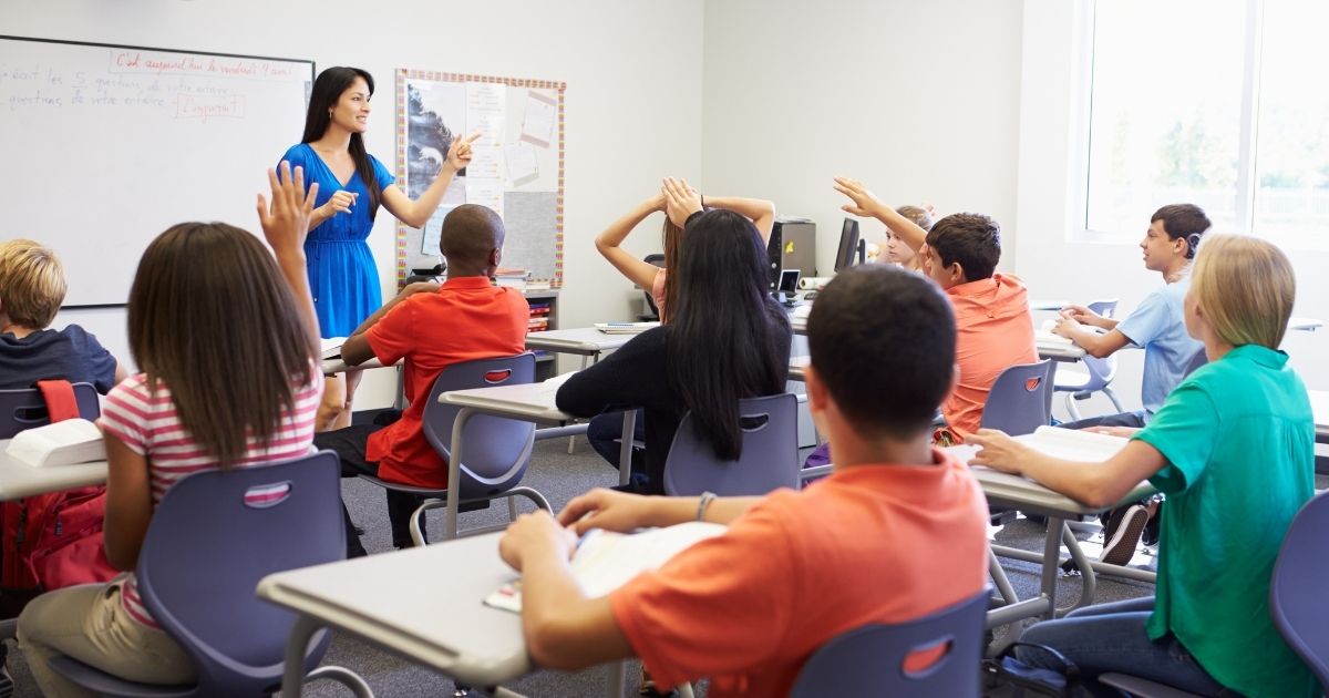 A teacher and her classroom of students are pictured above.
