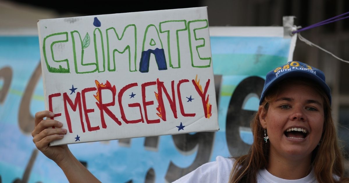 A protester holds a sign decrying climate change on Jan. 17, 2020, in Coral Gables, Florida.