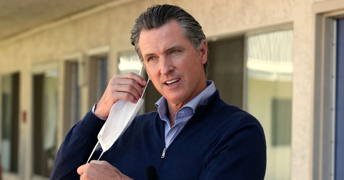 California Gov. Gavin Newsom removes his face mask before giving an update during a visit to Pittsburg, California, on June 20, 2020.