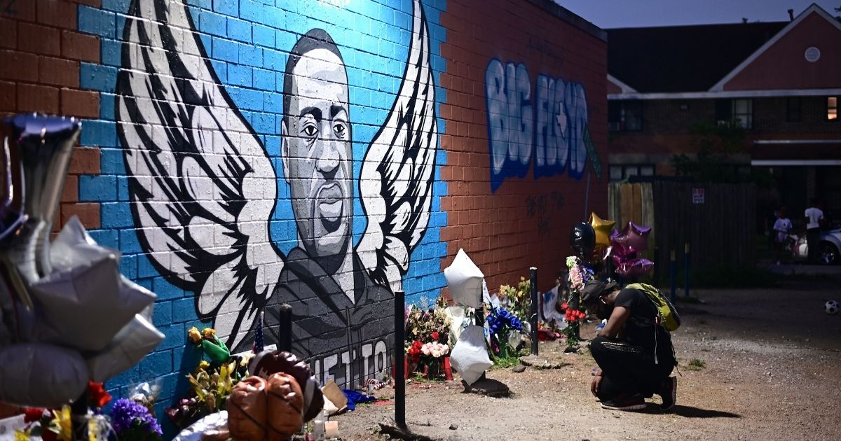 A man kneels in front of a mural of George Floyd in Houston on June 8.