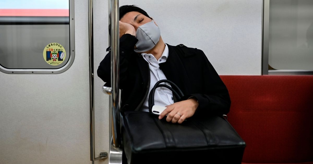A commuter wearing a facemask as a preventive measure against the coronavirus is seen on a train in Tokyo late on the evening of Nov. 17.