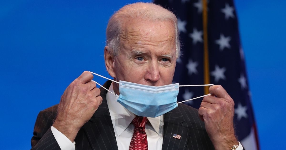 Democratic presidential candidate Joe Biden removes his protective mask as he gets ready to speak during a news conference Thursday at the Queen Theater in Wilmington, Delaware.
