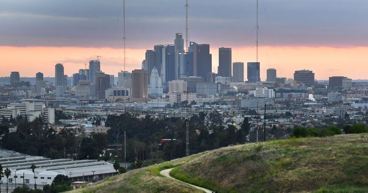 Hikers walk on a trail with a view of the Los Angeles city skyline in Los Angeles on April 20, 2020.