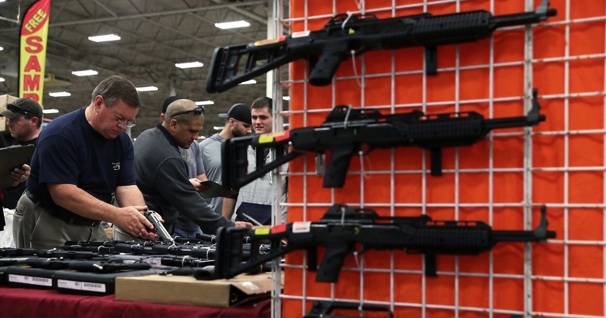 Potential buyers try out guns which are displayed on an exhibitor's table during the Nation's Gun Show on Nov. 18, 2016, at Dulles Expo Center in Chantilly, Virginia.