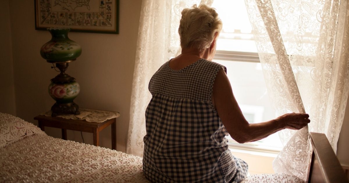 The stock photo above shows a woman looking out a bedroom window.