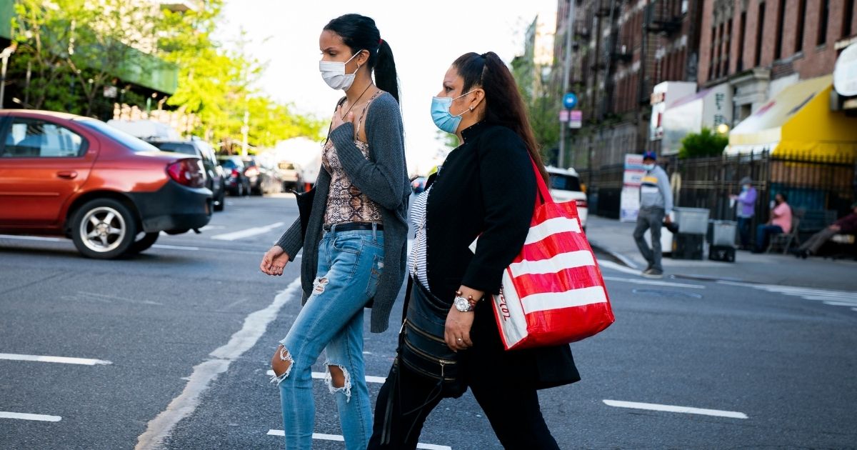 A woman and her teen daughter cross the street wearing medical masks in Manhattan, New York City, during the COVID-19 pandemic.