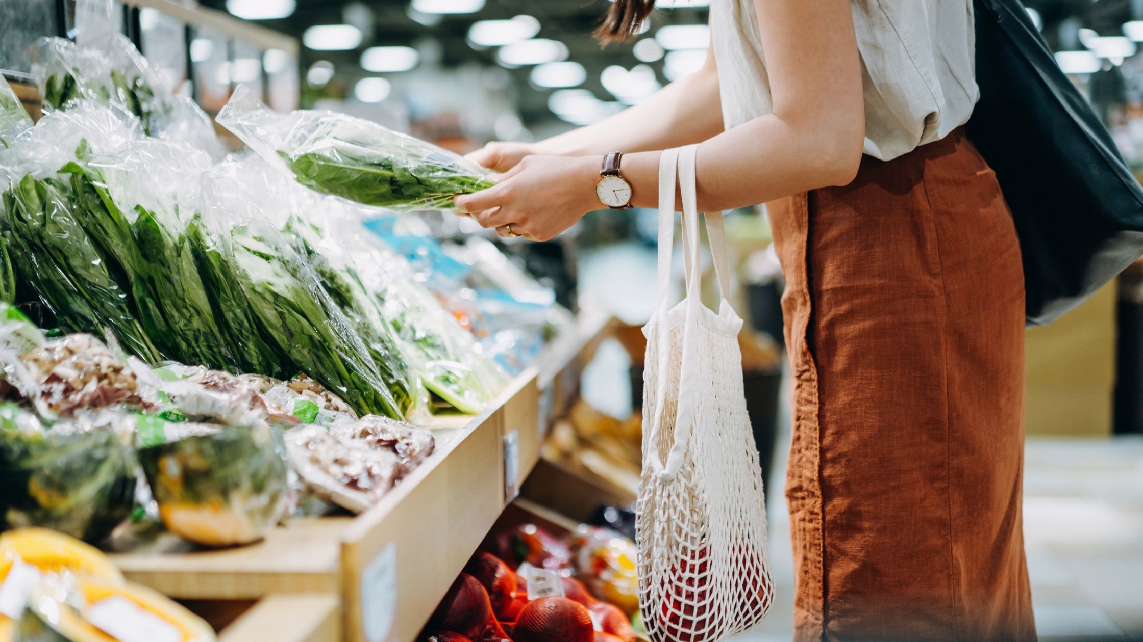 The above stock photo shows a woman shopping for produce at the store.