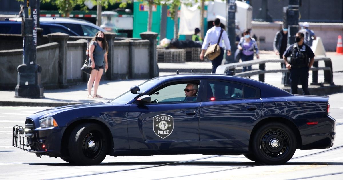 A Seattle police officer in his patrol car monitors a "Defund the Police" march in the city on Aug. 5.