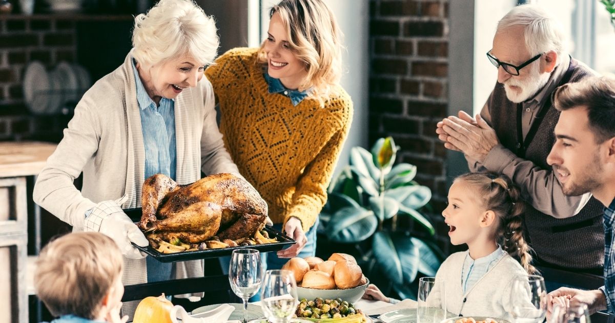 A grandmother serves a turkey to her family on Thanksgiving in the stock image above.
