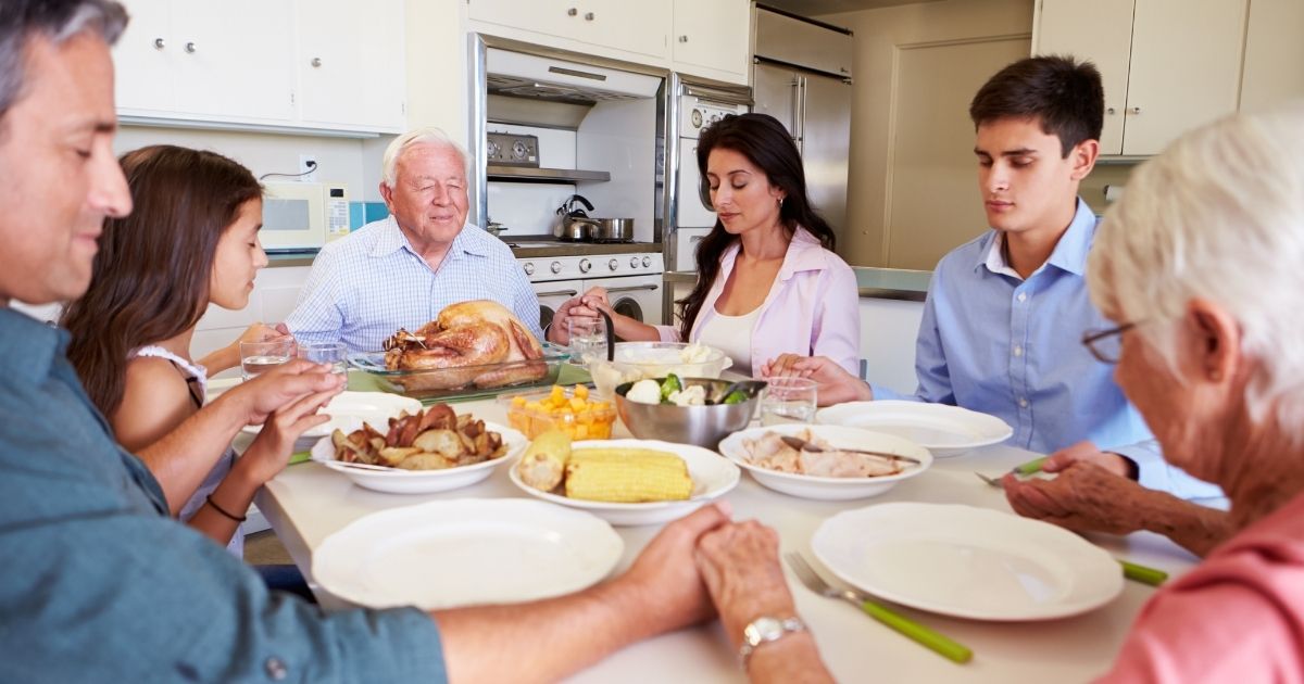 A family prays before eating Thanksgiving dinner.