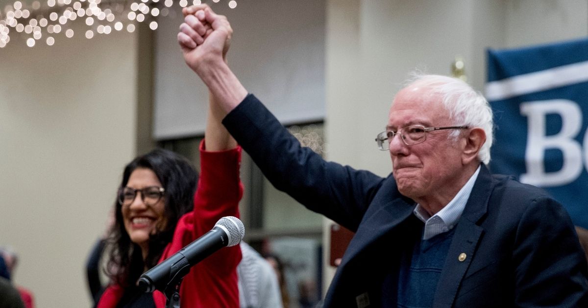 Democratic Rep. Rashida Tlaib of Michigan joins hands with Vermont Sen. Bernie Sanders during at a campaign event at St. Ambrose University in Davenport, Iowa, on Jan. 11.