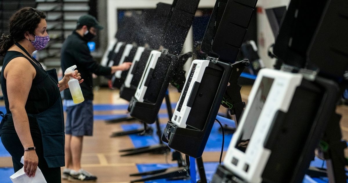 A volunteer disinfects a voting machine at an early voting center at the University of the District of Columbia on Oct. 27, 2020, in Washington, D.C.