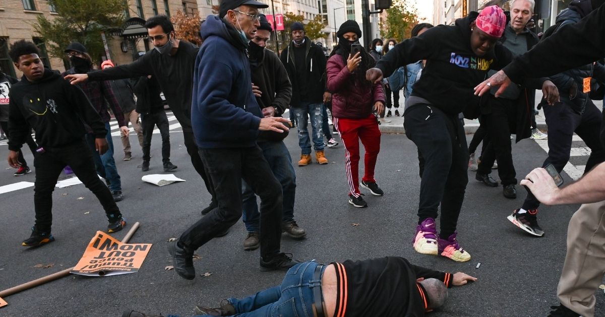 A supporter of President Donald Trump is kicked in the street after being knocked to the ground by anti-Trump demonstrators in Black Lives Matter Plaza in Washington on Saturday.