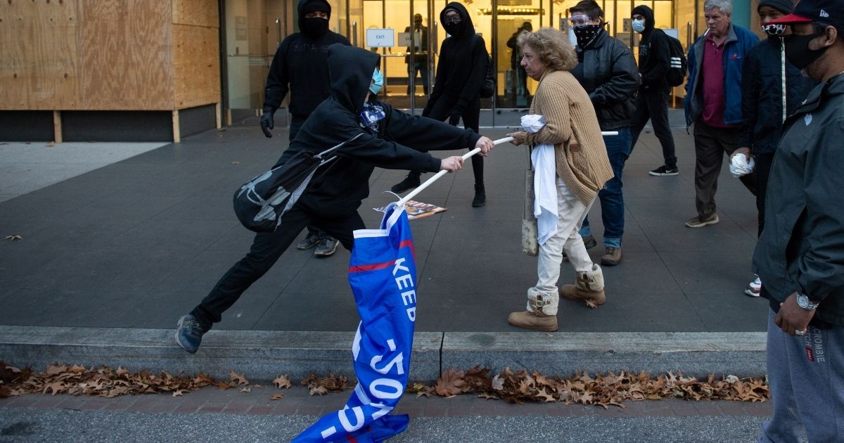 An anti-Trump attacker tries to wrest a flag from a supporter of President Donald Trump on Saturday in Washington.