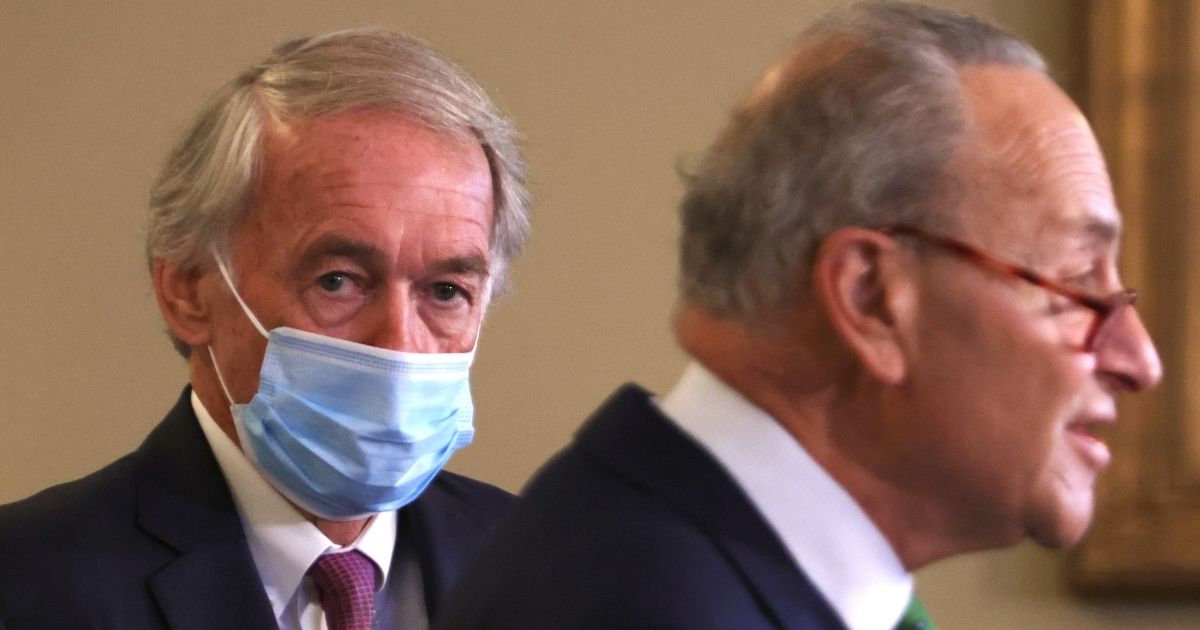A masked Massachusetts Sen. Edward Markey is pictured over the shoulder of Senate Minority Leader Chuck Schumer during a September news conference.